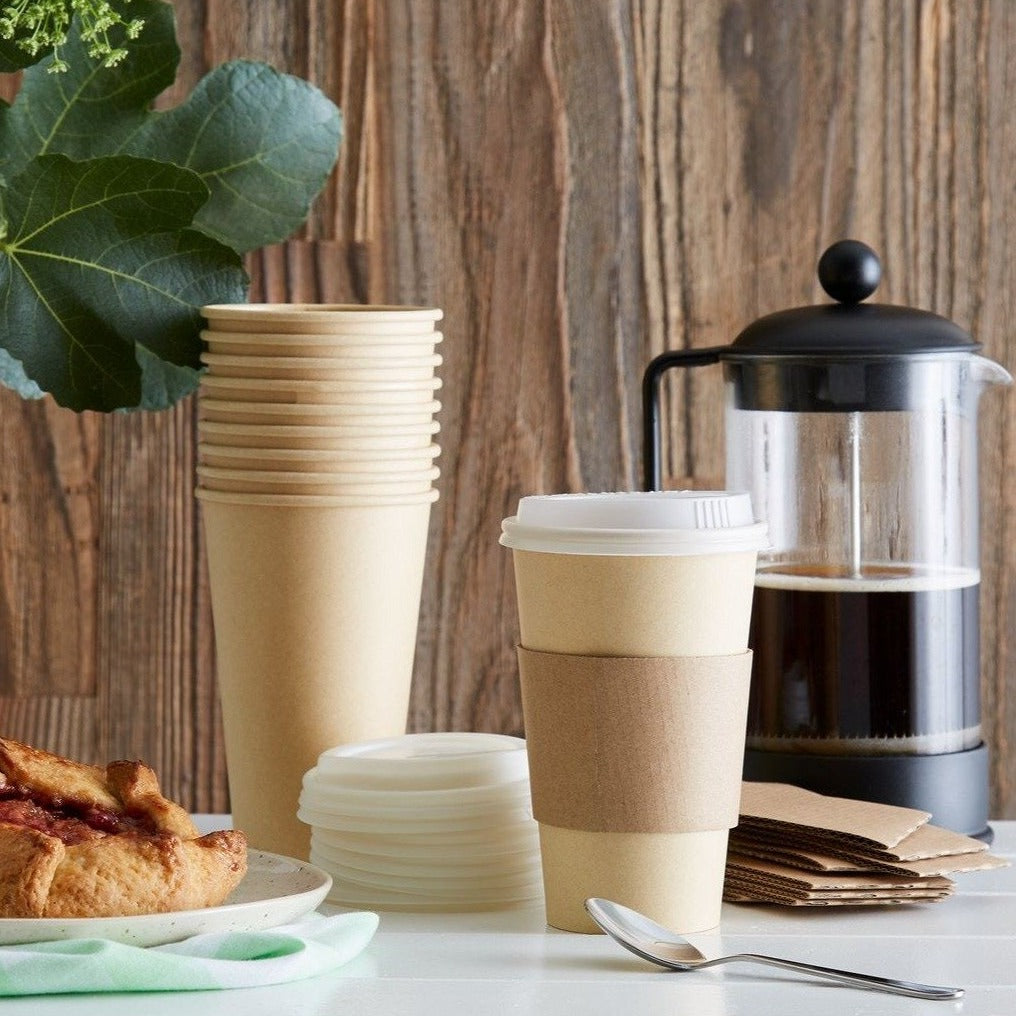 Lifestyle photo showing the Hot Beverge Cups Lids and Sleeves being used as breakfast coffee service next to a french press and a scone.