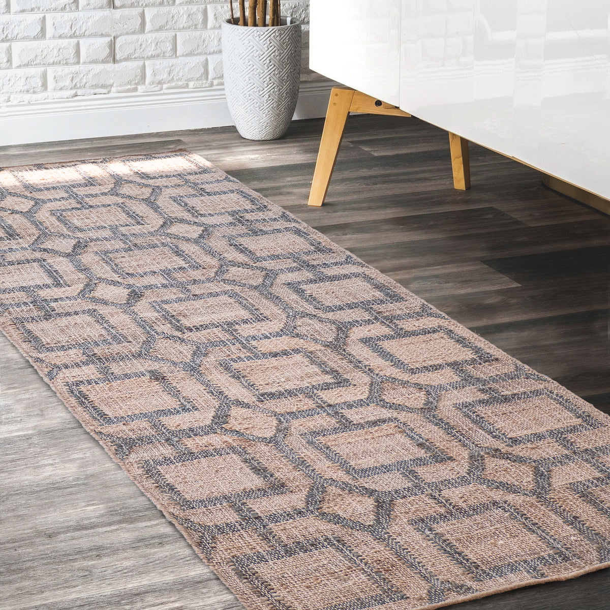 Lifestyle photo. Jute runner shown in an entryway next to a modern white couch against a gray-brown hardwood floor.