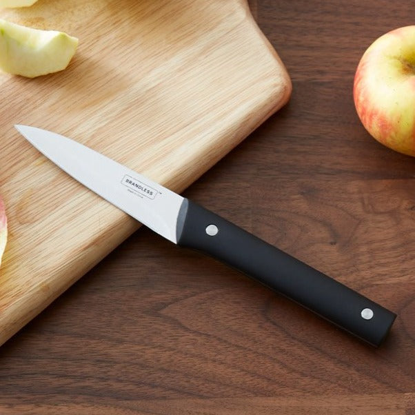 Lifestyle photo, paring knife laying on wood cutting board next to a quartered apple.