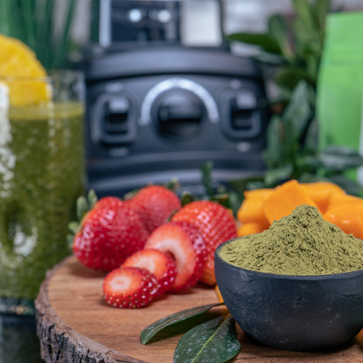 Lifestyle photo, Brandless Pro-blender in background, matcha powder in bowl, surrounded by other smoothie ingredients like strawberries, basil, squash.