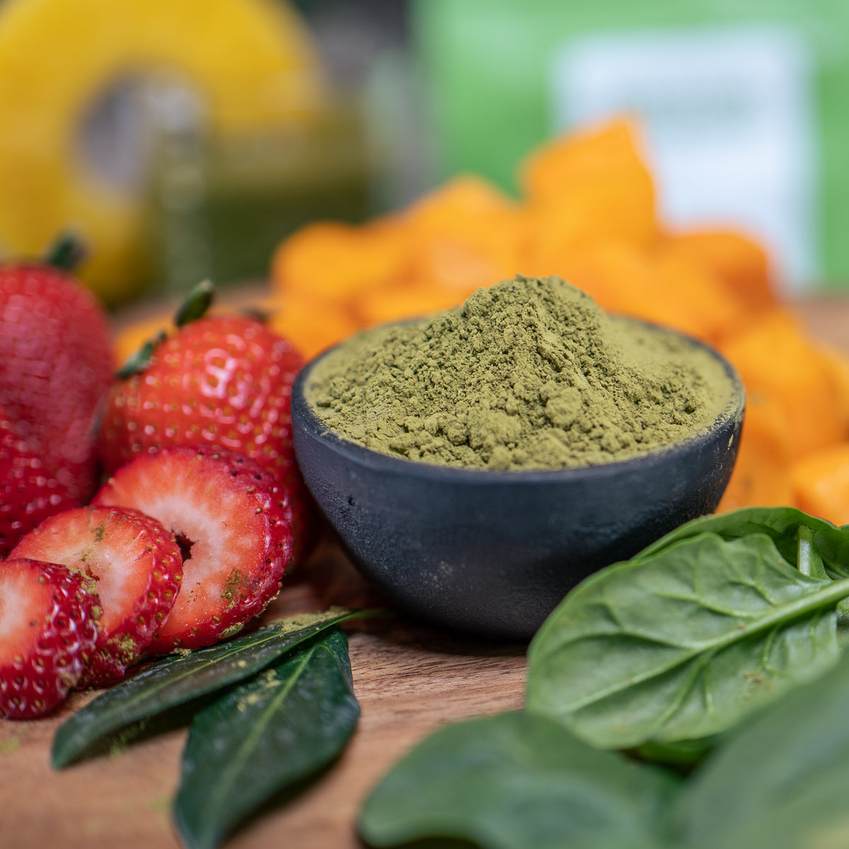 Lifestyle photo, matcha powder in bowl, surrounded by other smoothie ingredients like strawberries, basil, squash.