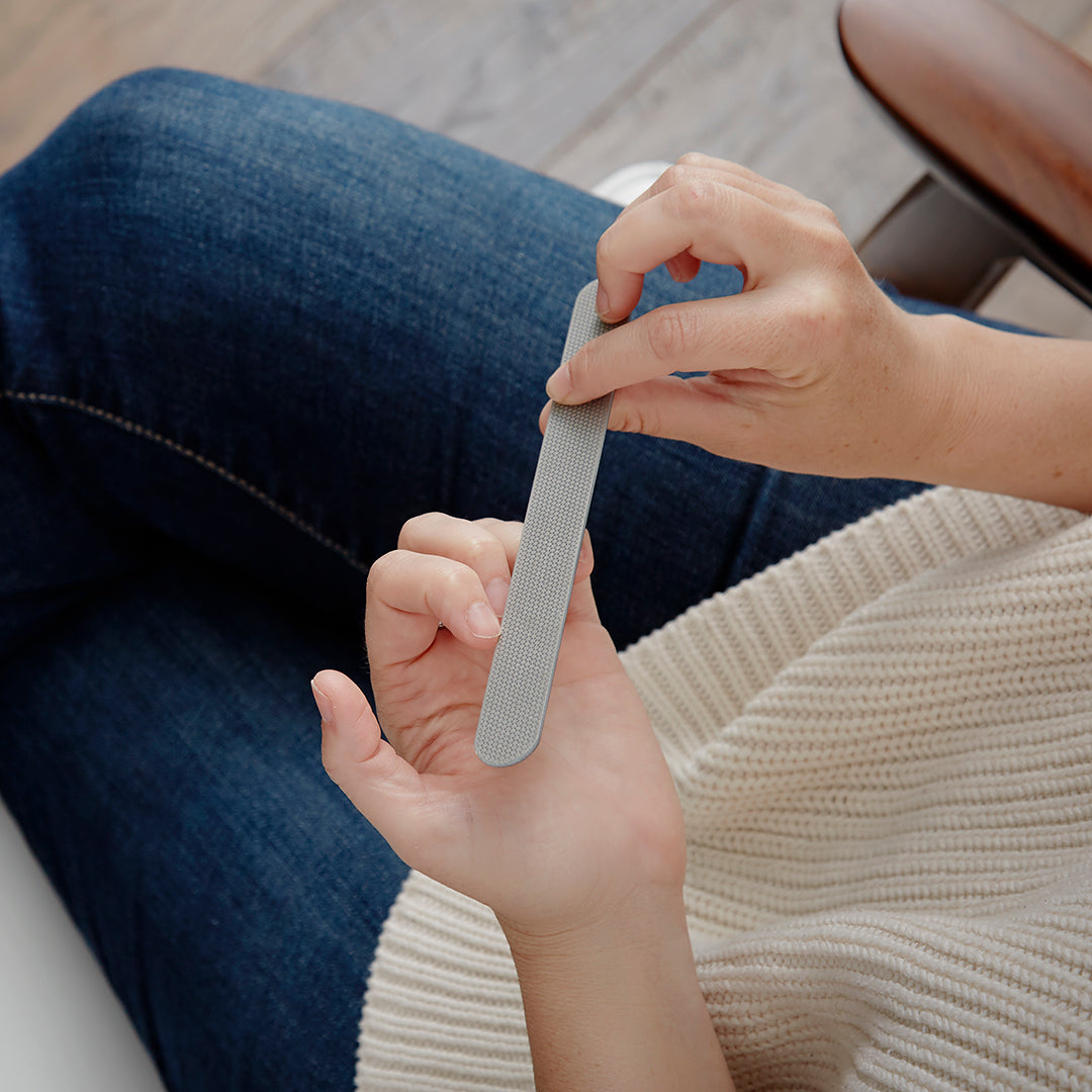 Lifestyle photo, woman completes some quick nail maintenance while seated.