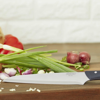 Lifestyle photo of the 8 inch chef's knife leaning on a cutting board with onions, shallots, and peppers on it.