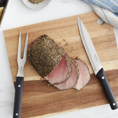 Lifestyle photo, carving knife and carving fork resting on a cutting board next to a nicely sliced pork loin.