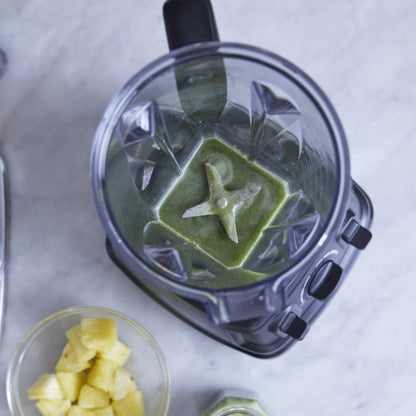 Top view of blender with a small amont of leftover green smootie in it, highlighting the stainless steel mixing blades at the bottom of the carafe.